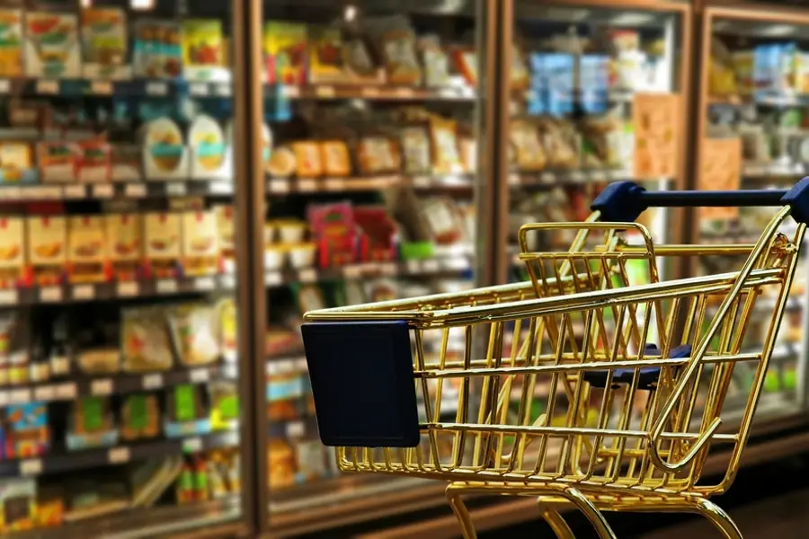 Well-stocked shop aisle with a shopping trolley